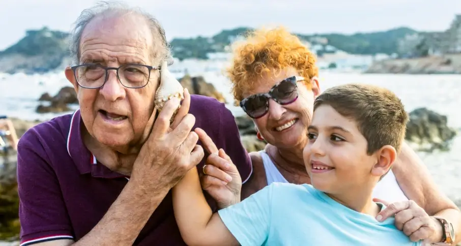 Grandparents enjoying time with grandchild at the beach.